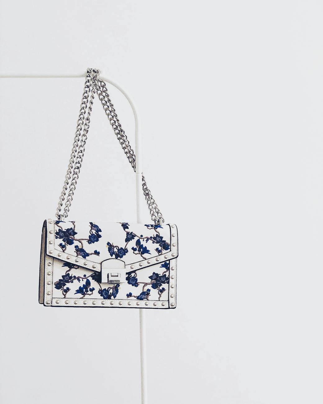 white and blue floral flap sling bag hanging on white steel rack