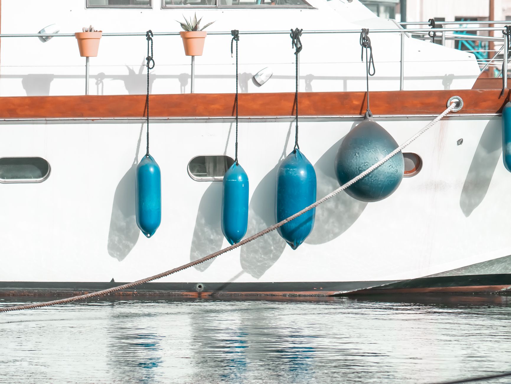 white yacht with blue fenders at dock